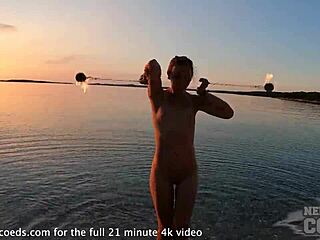 Nude fire dancer performs on usa beach at sunset